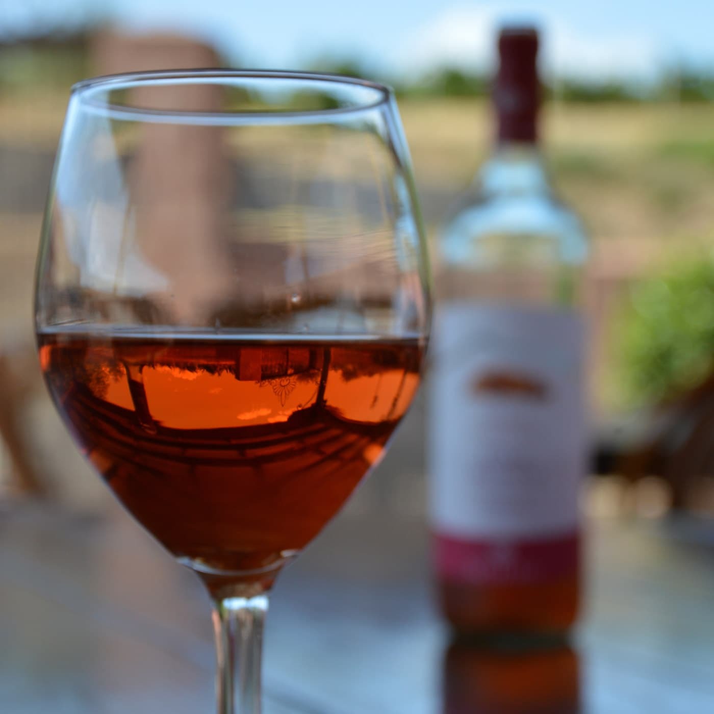 bicchiere mezzo pieno di vino con bottiglia di vino Scilio in secondo piano